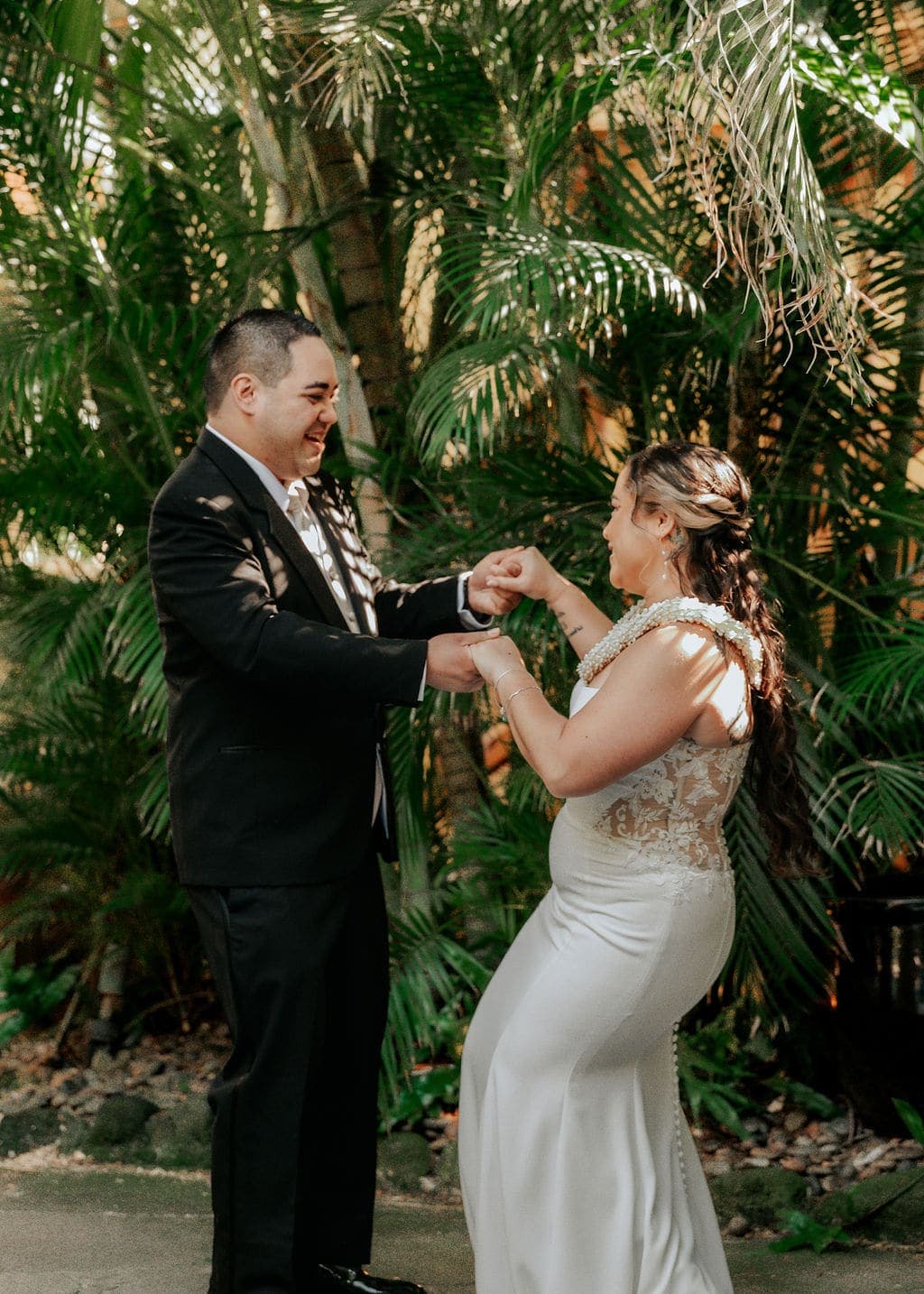 Bride and groom laughing together during their first look under the palms